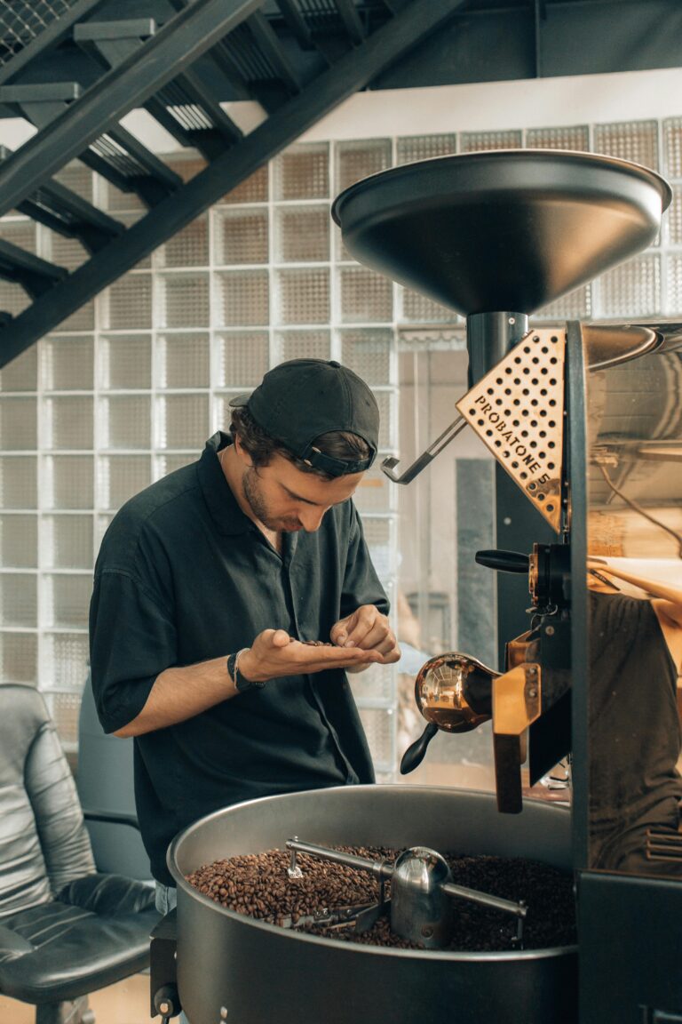 Man carefully examining coffee beans during the roasting process in a modern facility.